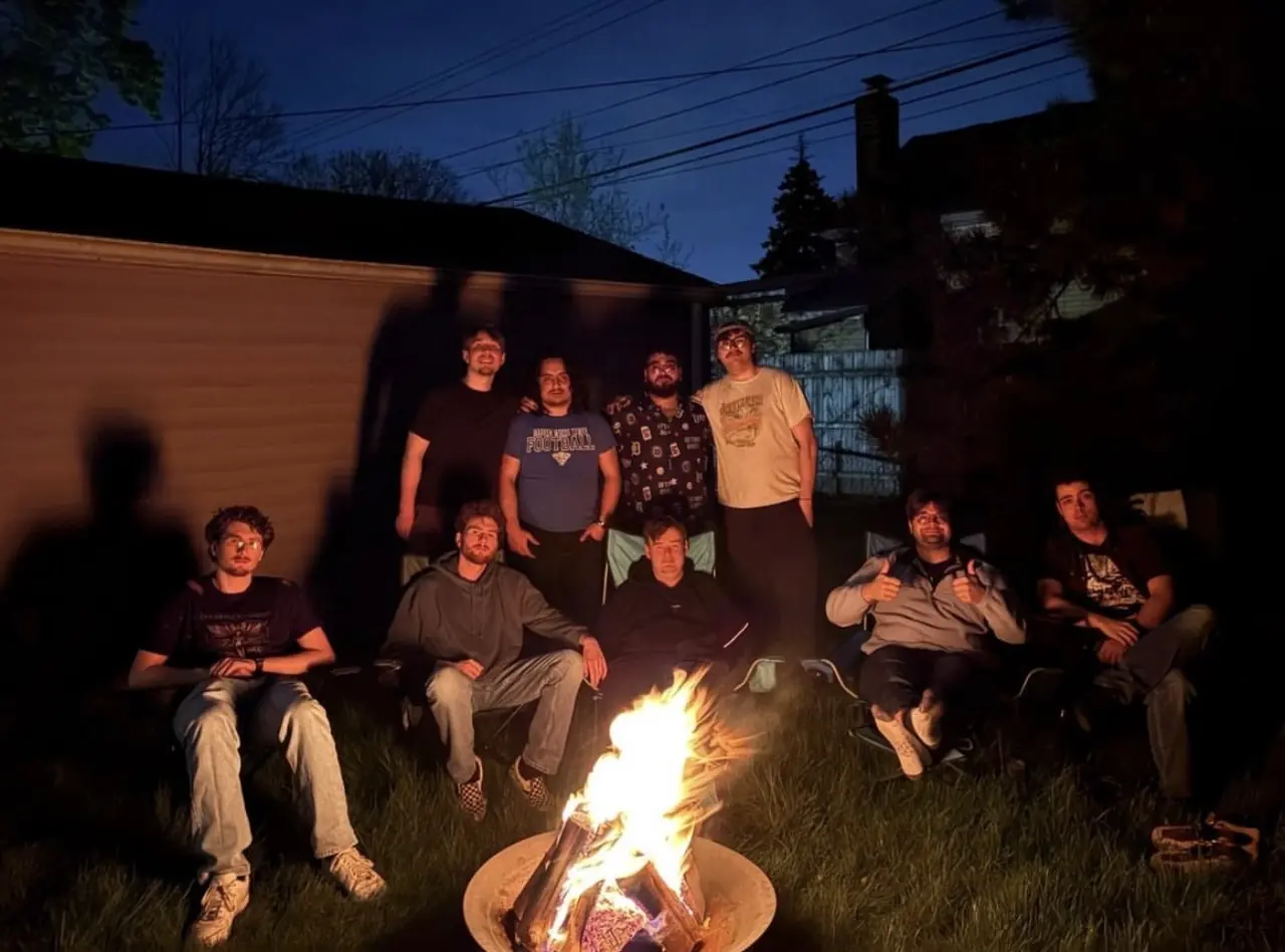 Brothers gathered around a backyard fire at dusk.
